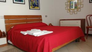 a bed with red sheets and white towels on it at Appartamento Balconcino su Lazise in Lazise +25 photos
