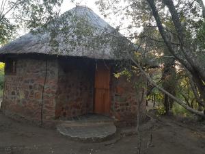 umbabala bush camp في روستنبرج: مبنى من الطوب صغير مع سقف من العشب