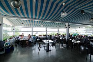 a restaurant with a blue ceiling with people sitting at tables at Hotel Belona in Eforie Nord