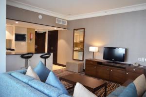 a living room with a blue couch and a flat screen tv at Copthorne Downtown by Millennium in Abu Dhabi