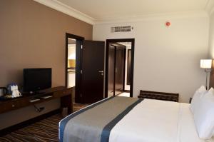 a hotel room with a bed and a television at Copthorne Downtown by Millennium in Abu Dhabi