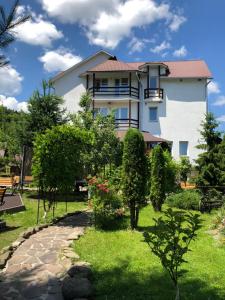 a large white house with a garden in front of it at Smerekovyi Dvir in Zhdenievo
