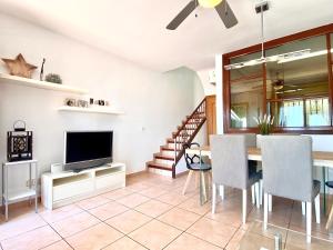a living room with a dining room table and a television at Casa cómoda delante de la playa con vista al mar in Cambrils