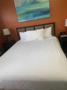 a large bed with white sheets and pillows at The Triangle Motel in Alma