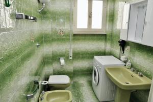 a green tiled bathroom with a toilet and a sink at Central Holiday Home Sperlonga in Sperlonga +29 photos