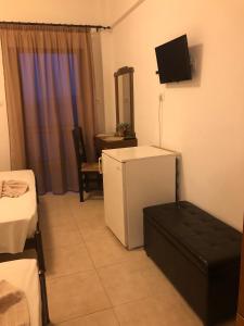 a room with a refrigerator and a tv on the wall at Hotel Avra in Ouranoupoli