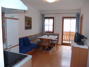 瓦爾道拉的住宿－Appartement Gandler，厨房以及带桌子和蓝色沙发的客厅。