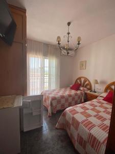 a hotel room with two beds and a chandelier at Pensión Mari Carmen in Salobreña