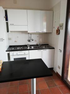uma cozinha com armários brancos e um balcão preto em Casa delle lantane climatizzata em Villaputzu