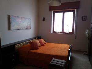 1 dormitorio con cama con sábanas de color naranja y ventana en Appartamento vicino al mare en Giardini Naxos