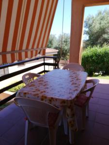 uma mesa e cadeiras num pátio com um guarda-sol em Casa delle lantane climatizzata em Villaputzu