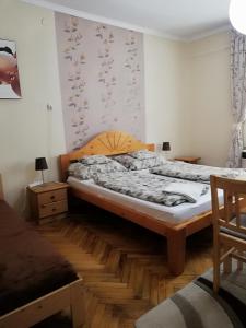 a bedroom with a bed and a wooden floor at Csilla Apartman in Makó