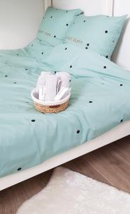 Bett mit einem Korb mit Handtüchern und Kissen in der Unterkunft Alegria Newport in Koksijde
