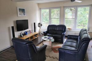 sala de estar con sillas de cuero negro y TV de pantalla plana en Bohmte Zuhause mit Aussicht, en Bohmte