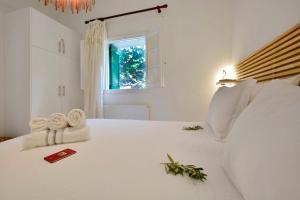 a white bedroom with a bed with towels and a window at Minimalist Cozy House in Corfu