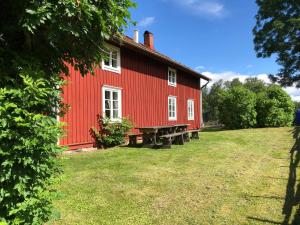 ein rotes Haus auf einem Grasfeld neben einem Gebäude in der Unterkunft Vandrarhem Lövö in Hillerstorp