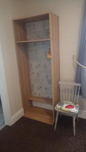 a wooden closet with a white chair next to it at The Victoria guest house in Mablethorpe