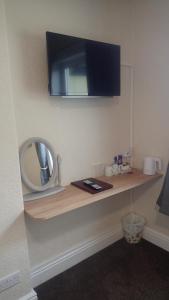 a bathroom with a shelf with a mirror and a tv at The Victoria guest house in Mablethorpe