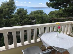 una mesa y sillas en un balcón con vistas al agua en Villa Rosso en Baška Voda