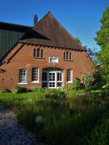 a large brick building with white windows and a yard at Pottkiekerhus in Luhnstedt