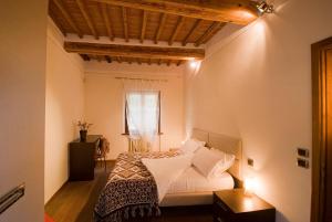 a bedroom with a bed with white sheets and a window at Vicolo dell'Oste in Montepulciano