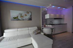 a living room with a white couch and a kitchen at Gardenia Sea Side MARTINA 2 Dziwnów in Dziwnów