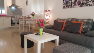 ein Wohnzimmer mit einem Sofa und einem Tisch mit Blumen darauf in der Unterkunft Apartments BRIST HILLS in Pula