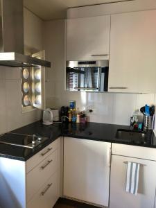 a kitchen with white cabinets and black counter tops at HSH Breitenrain - Serviced Apartment - Bern City by HSH Hotel Serviced Home in Bern