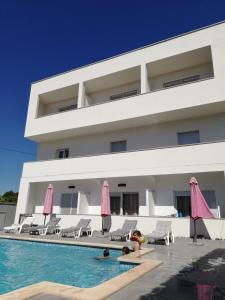 een gebouw met een zwembad en roze parasols bij Apartmant & rooms Villa Rosa Medulin in Pomer