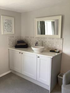 Birtles Farm Bed and Breakfast في كنوتسفورد: حمام مع حوض أبيض ومرآة
