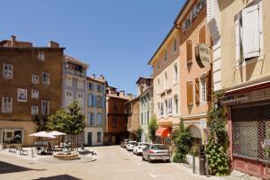 una calle en una ciudad con edificios y coches en Hôtel Le Lons, en Foix
