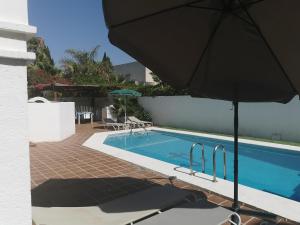 uma piscina com um guarda-sol ao lado de uma casa em Villa PaloMayor em Vera