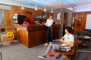 a woman standing behind a bar in a restaurant at Hôtel Le Lons in Foix