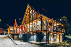 una casa de madera con una gran terraza por la noche en Chalet Valcanale, en Camporosso in Valcanale