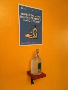 un cartel colgado en una pared con una botella en un estante en Albergue Azabache, en Santiago de Compostela