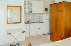 La cuisine est équipée de placards blancs, d'un lavabo et d'un miroir. dans l'établissement RONZI APARTMANT, à Kamena Vourla