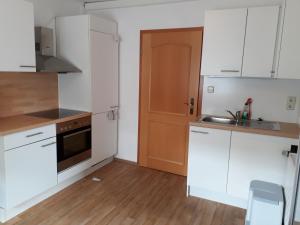 a kitchen with white cabinets and a wooden floor at Ferienwohnung Pries in Kiel +4 photos