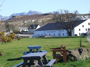 dos mesas de picnic en un campo frente a un edificio blanco en Trien Lodge, en Carbost