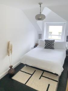 a bedroom with a white bed and a window at Causeway Coast Townhouse in Ballycastle