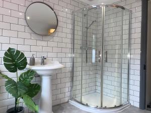 uma casa de banho com um chuveiro, um lavatório e um espelho. em Causeway Coast Townhouse em Ballycastle