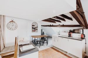 a kitchen with white walls and a clock on the wall at L'échappée in Bourges