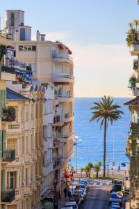 un grand bâtiment avec un palmier à côté de l'océan dans l'établissement LE CLIO CARRÉ D'OR BEACH APARTMENT, à Nice