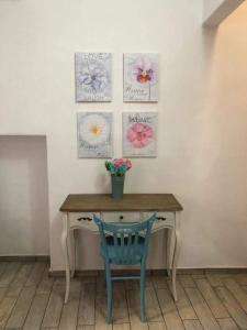 una mesa con una silla azul y pinturas en la pared en Il Girasole, en Iglesias