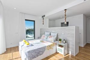 een witte slaapkamer met een bed en een raam bij Villa Ohana in Albufeira +15 foto's