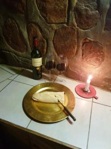 umbabala bush camp في روستنبرج: طبق من الطعام على طاولة مع شمعة وكؤوس للنبيذ