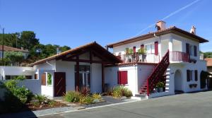 uma casa branca com uma porta vermelha e uma varanda em Location Fantaisie Ondres em Ondres