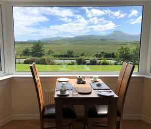 einem Tisch mit Stühlen vor einem großen Fenster in der Unterkunft Kilmuir Park in Dunvegan