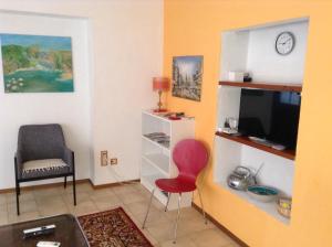 ein Wohnzimmer mit einem roten Stuhl und einem TV in der Unterkunft Verzaschina in Gordola