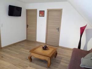 a living room with a coffee table and a tv at Gîte des Garennes in Saint-Étienne-au-Mont