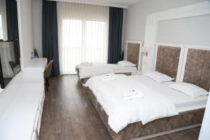 two beds in a room with white walls and wooden floors at Sky Hotel in Prizren